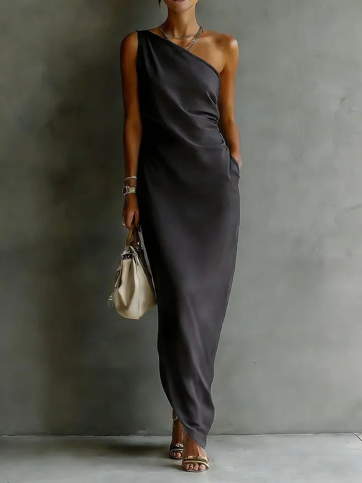 Woman wearing a gray one-shoulder dress against a plain background