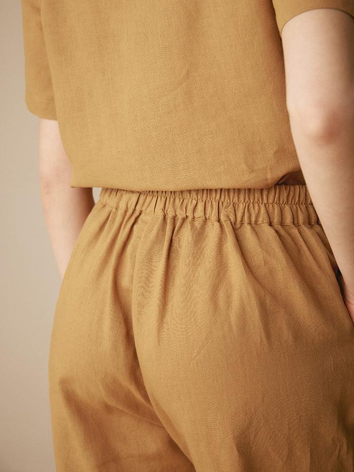 Person wearing a mustard yellow outfit with a plain background