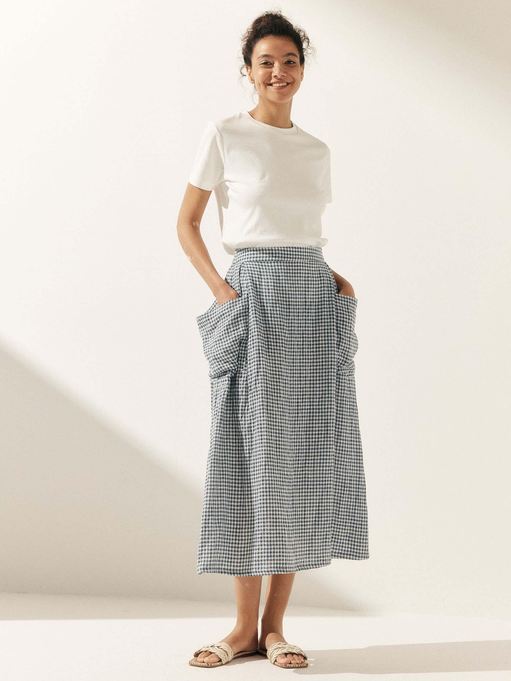 Woman wearing a white t-shirt and checkered skirt on a plain background