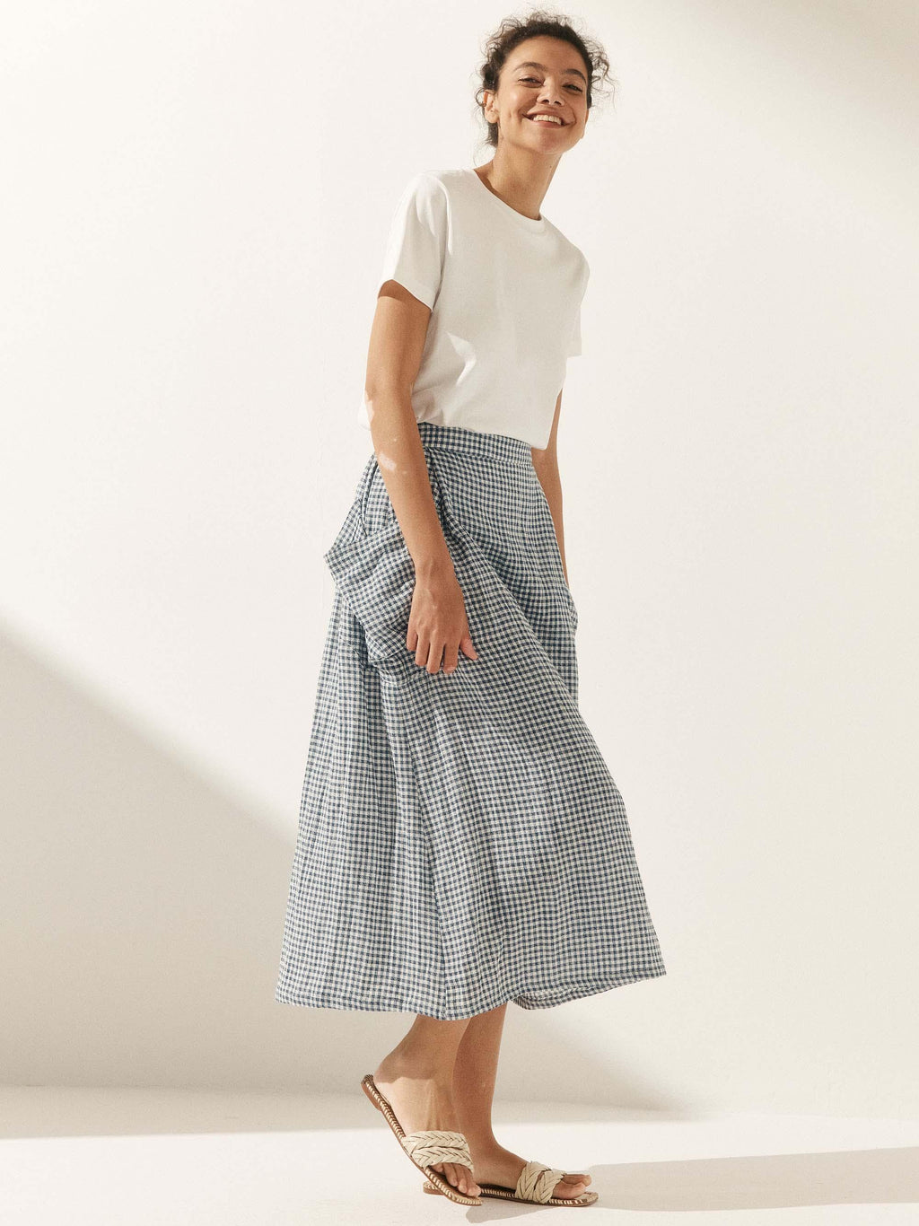 Woman wearing a white top and checkered skirt on a plain background