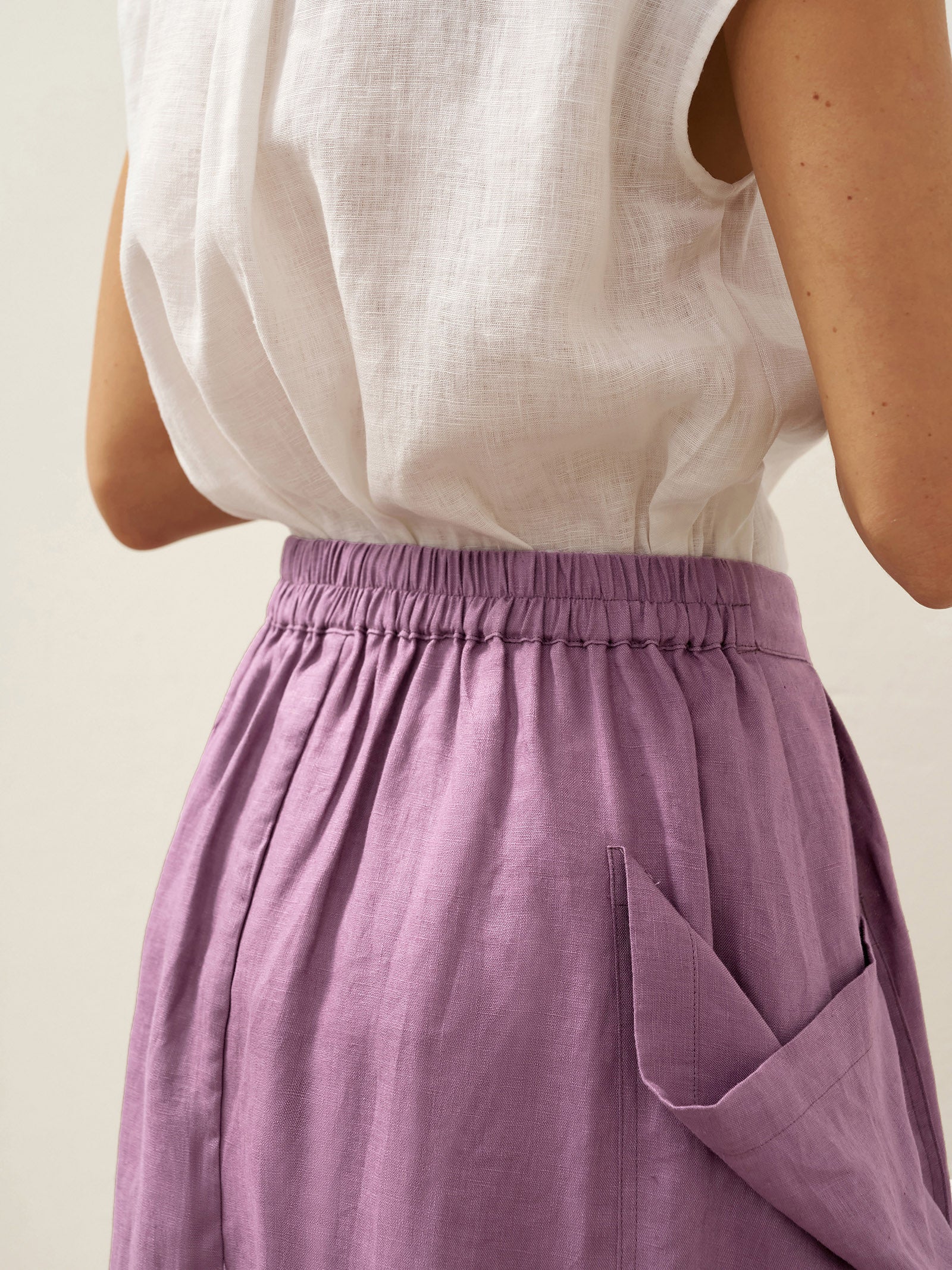Person wearing a white top and purple skirt on a plain background