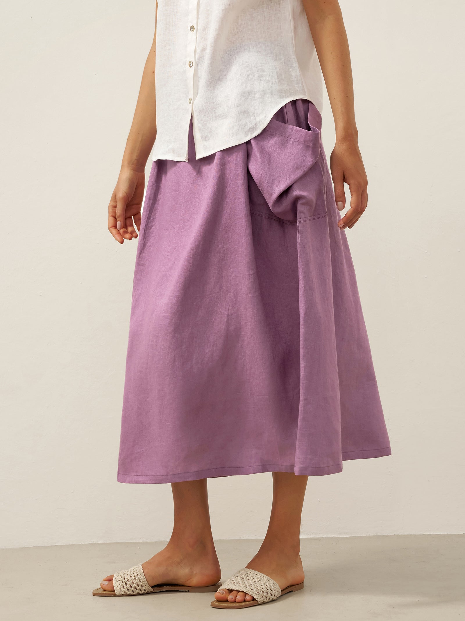Person wearing a white shirt and purple skirt on a plain background