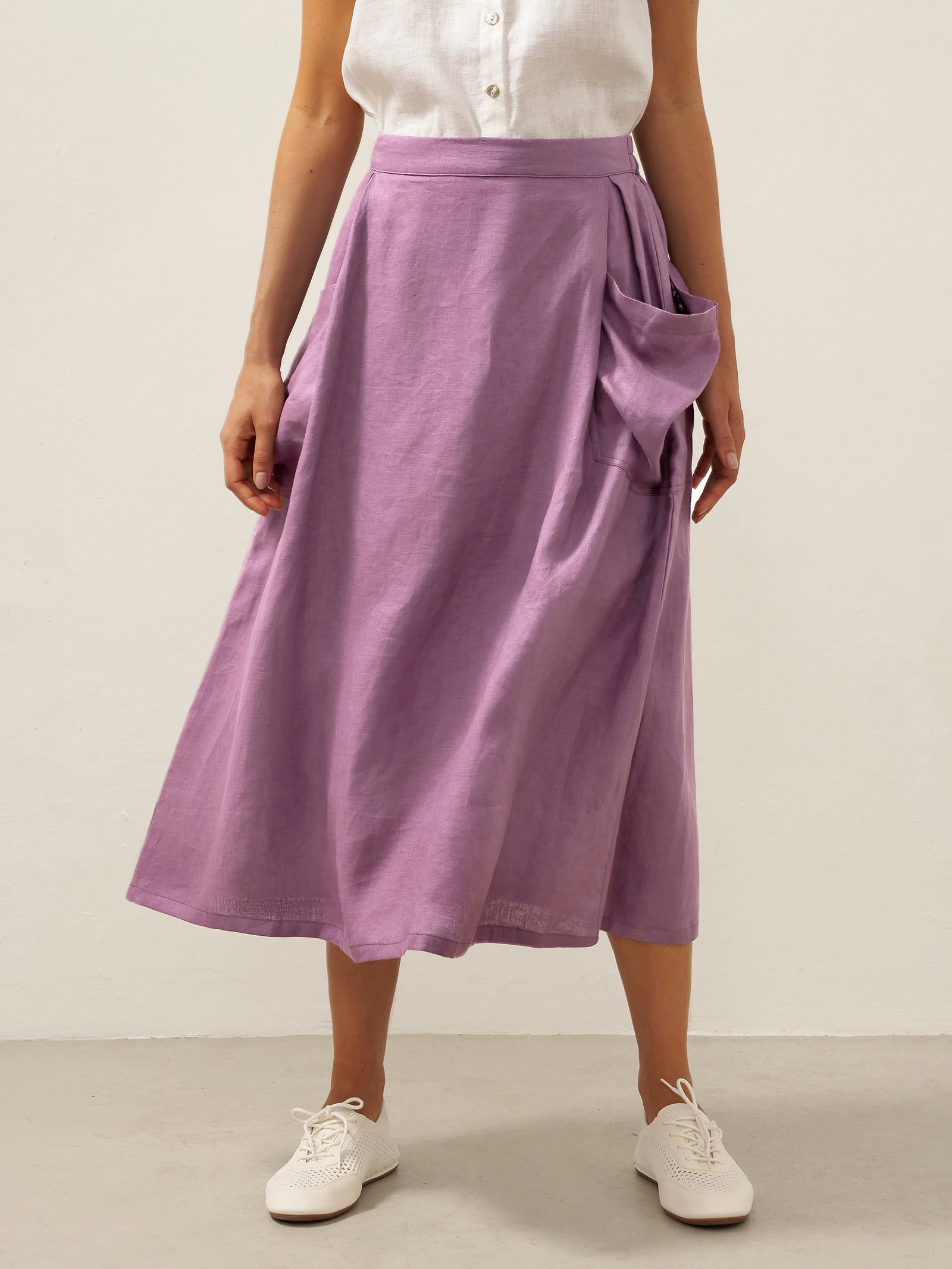 Person wearing a purple skirt and white shoes on a plain background