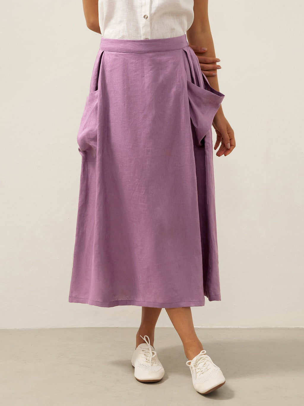 Person wearing a purple skirt and white shoes on a plain background