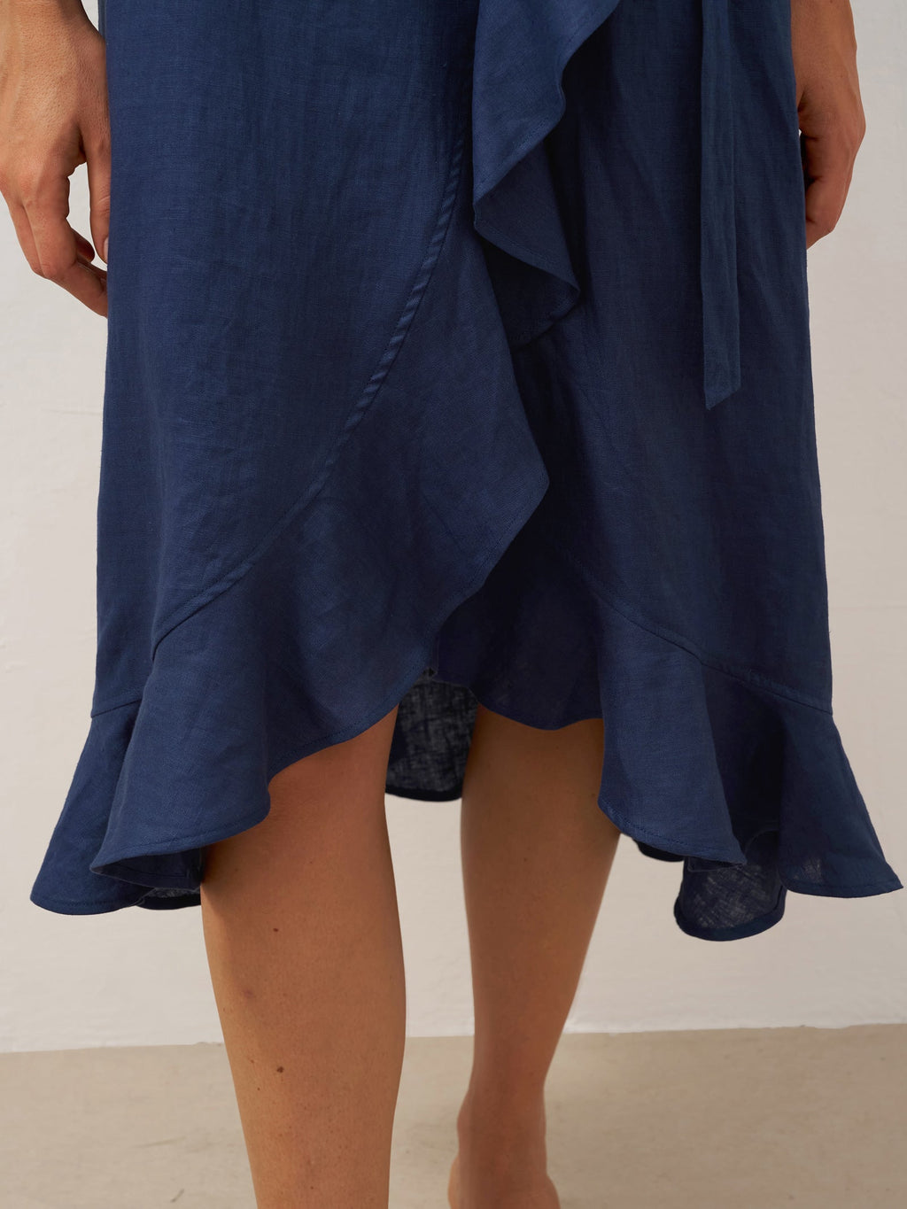 Navy blue dress with ruffled details on a plain background