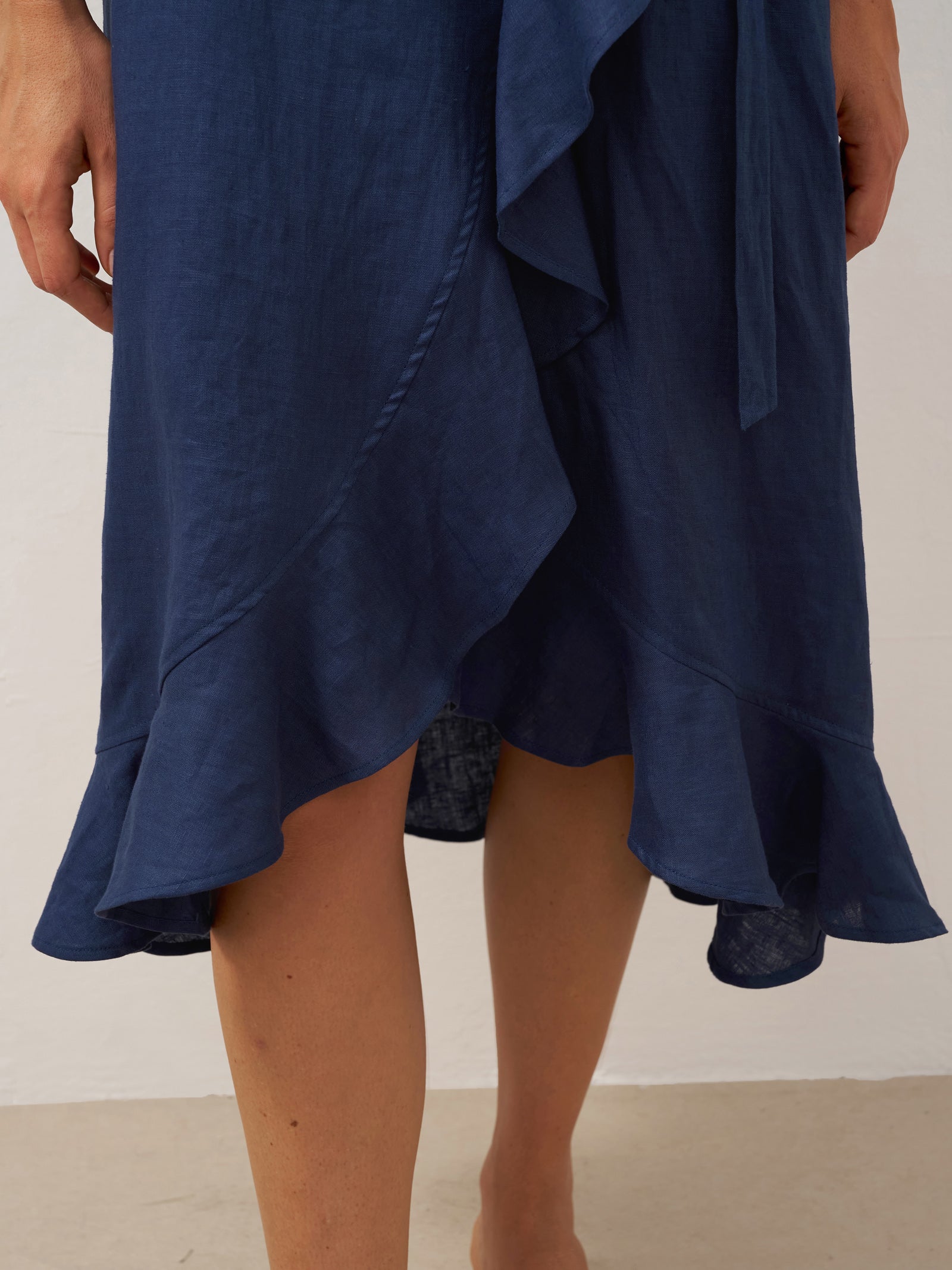 Navy blue dress with ruffled details on a plain background
