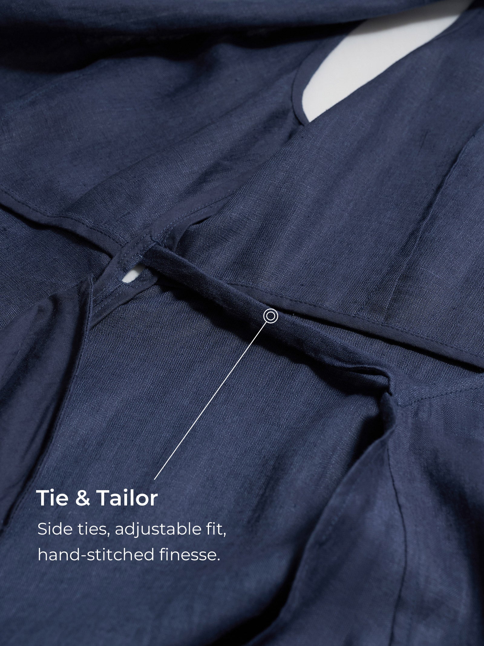 Navy blue garment with side tie feature and text indicating 'Tie & Tailor' brand.
