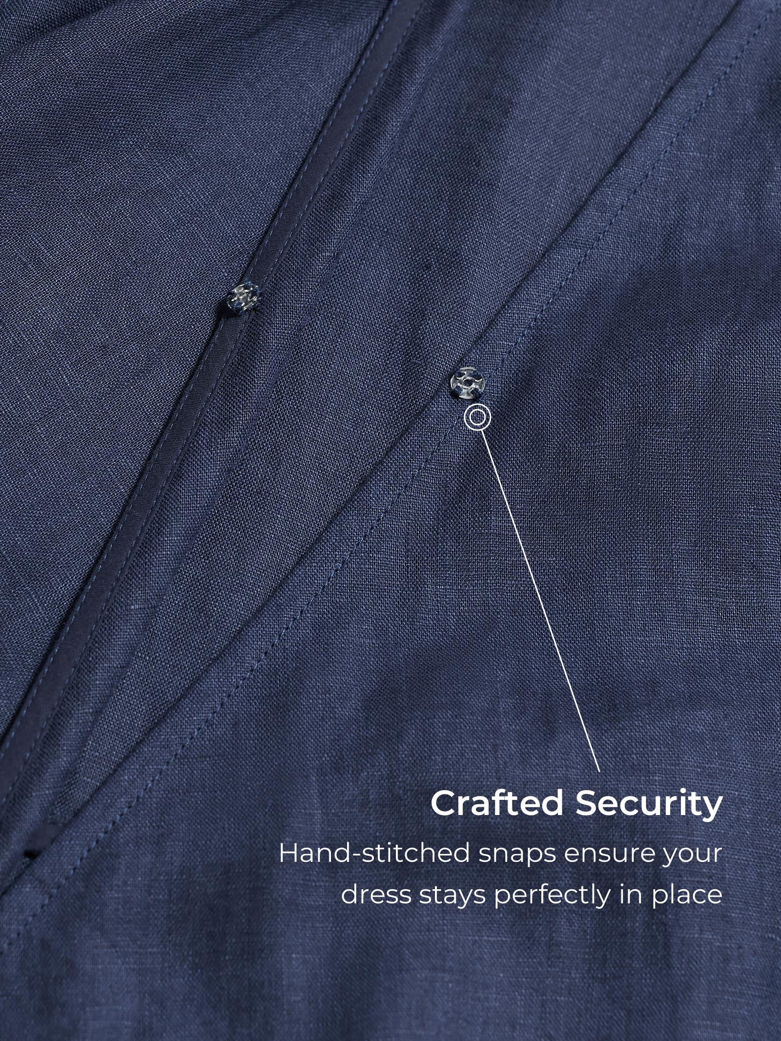 Close-up of a navy blue dress with hand-stitched snaps, labeled 'Crafted Security'.