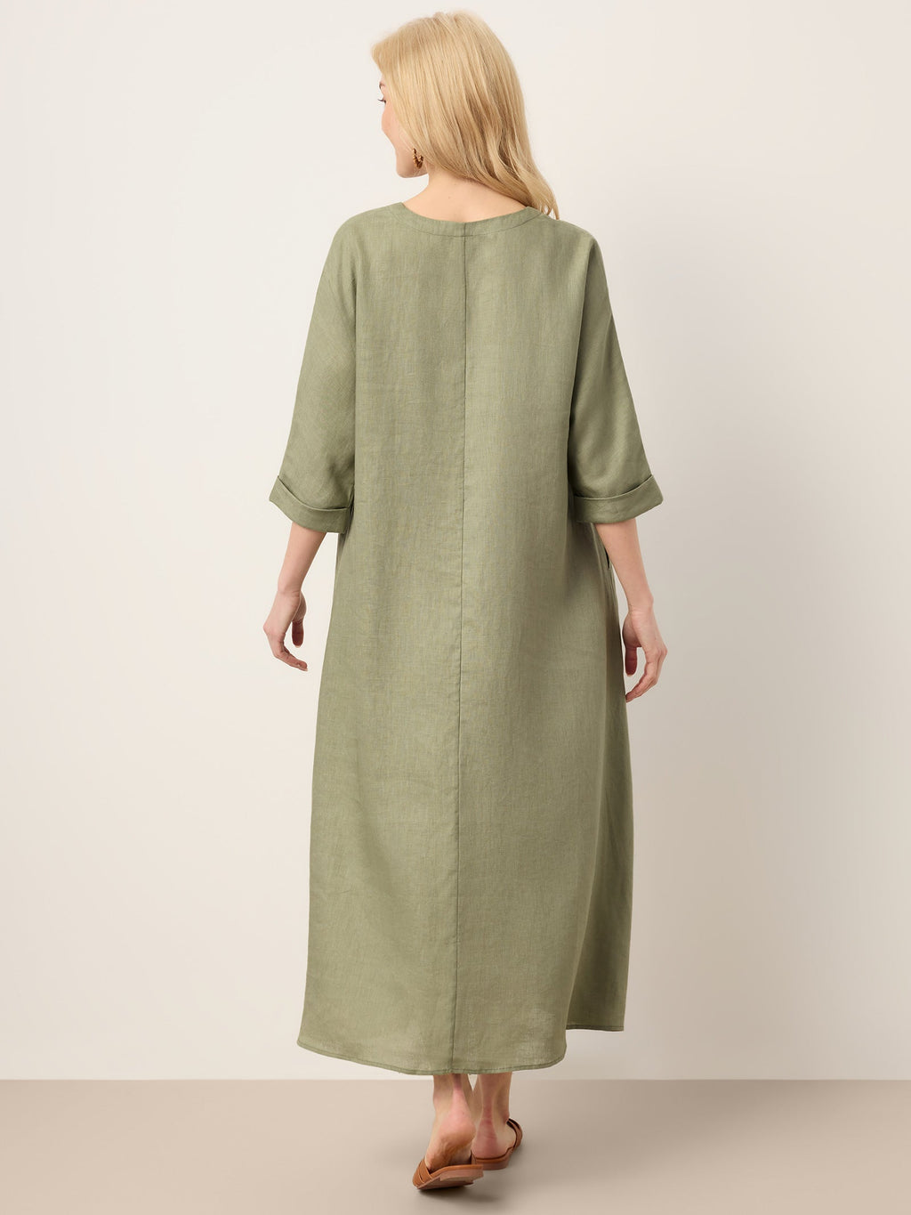 Woman wearing a long green dress on a plain background