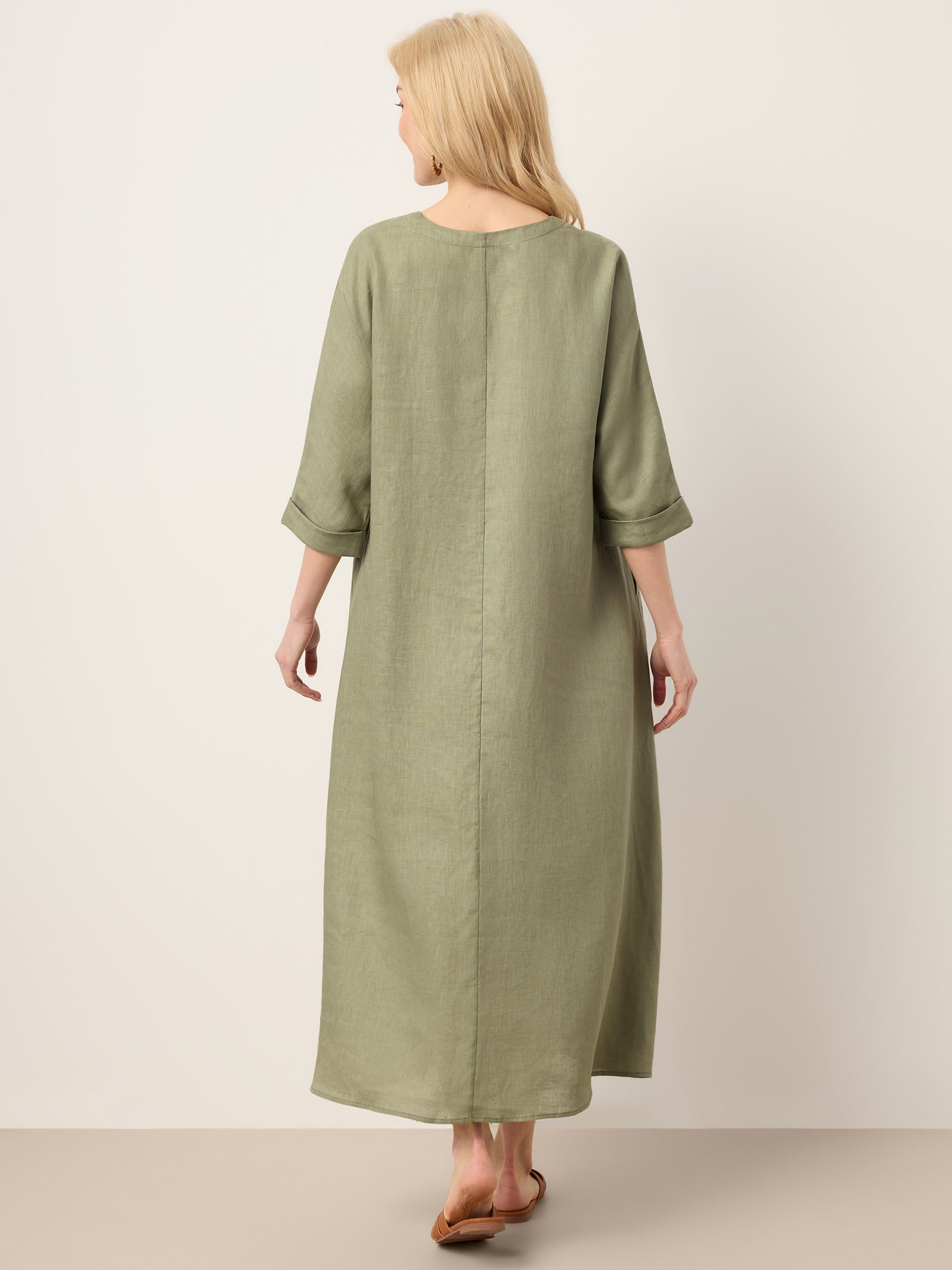 Woman wearing a long green dress on a plain background