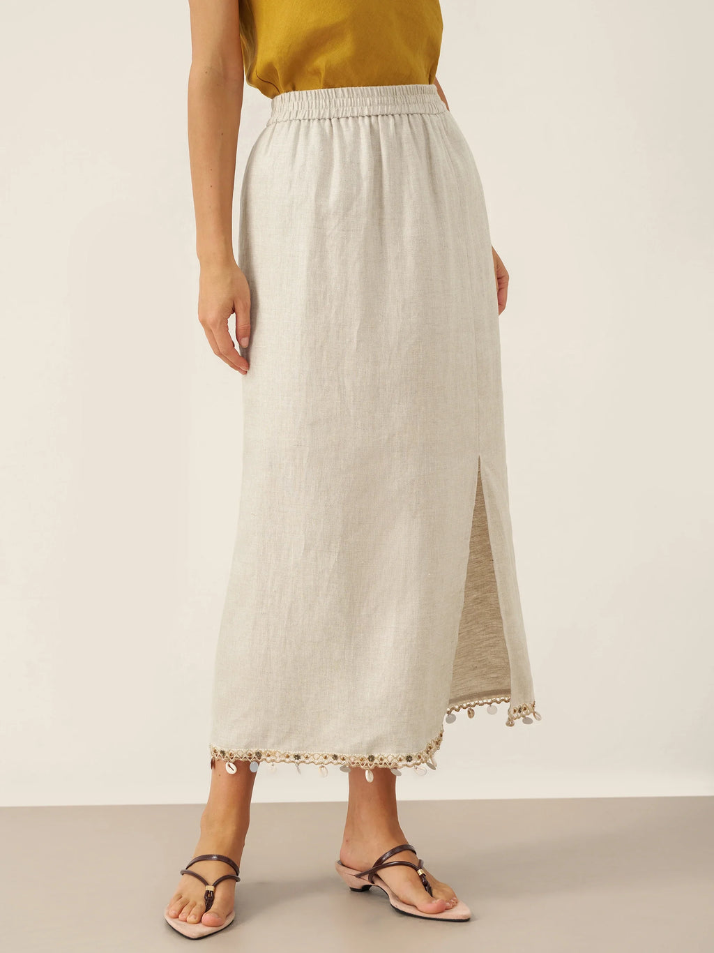Person wearing a white skirt with a subtle pattern on a plain background