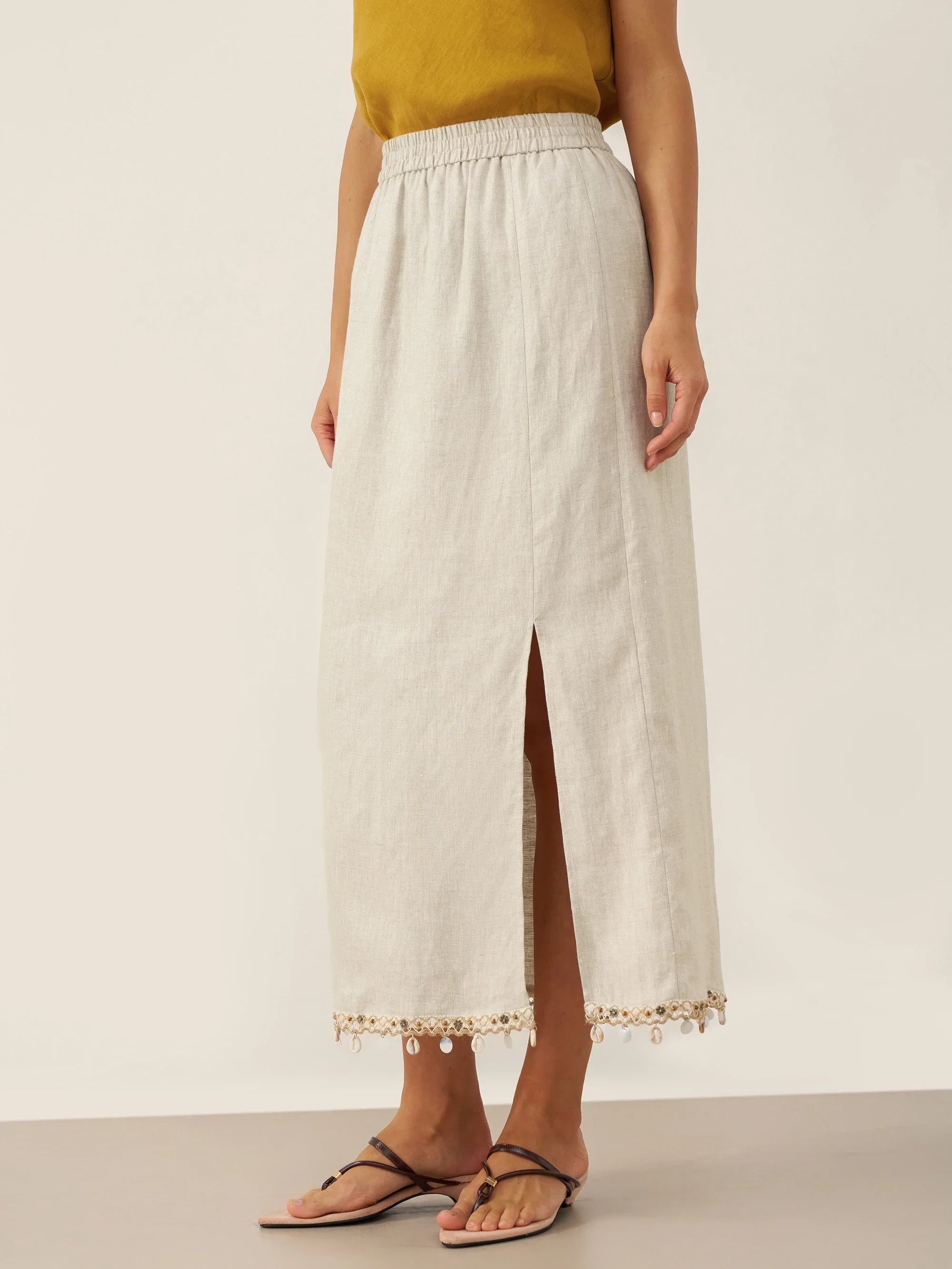 Woman wearing a white lace-trimmed skirt on a plain background