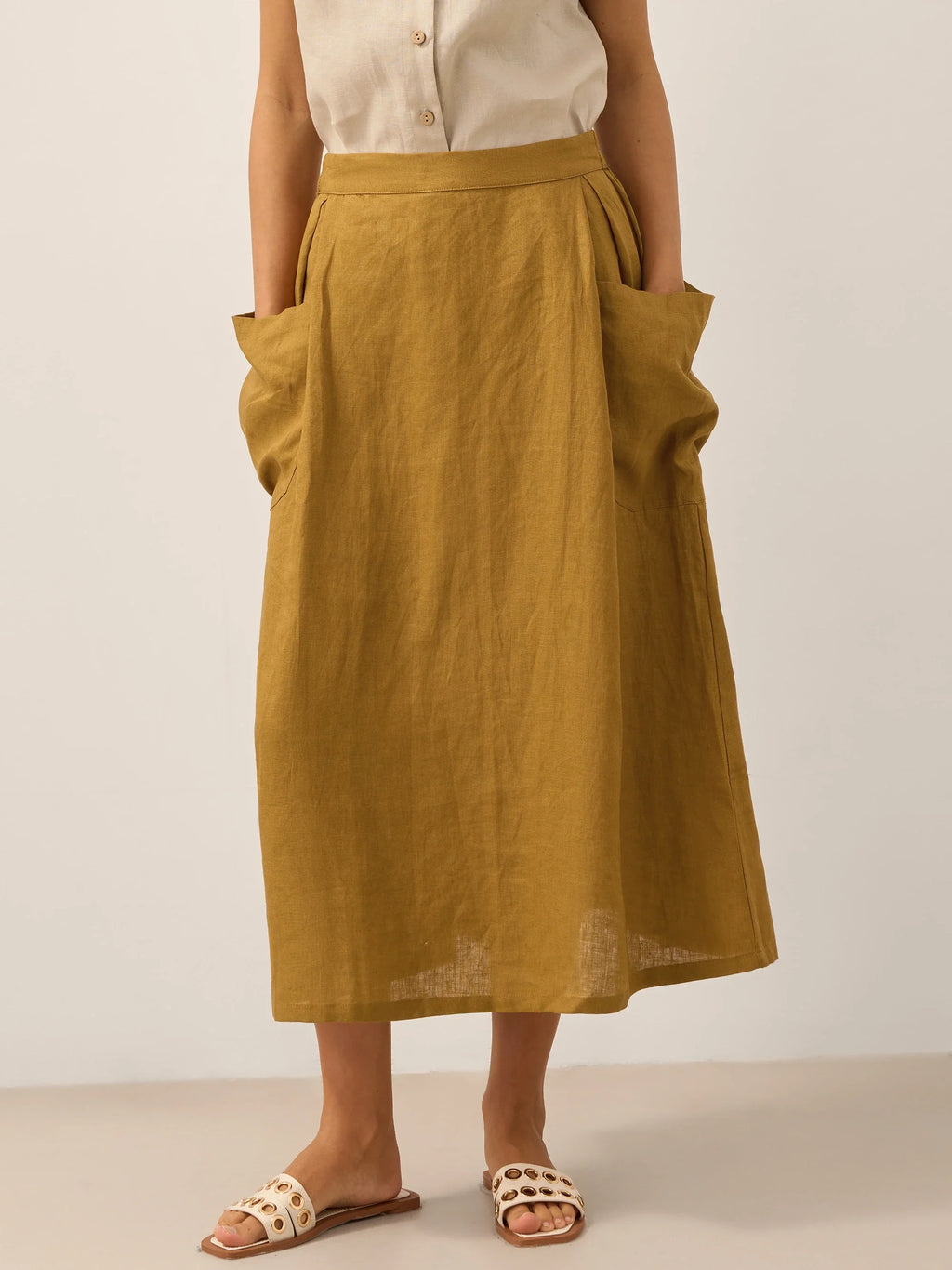 Person wearing a mustard yellow skirt with a plain background