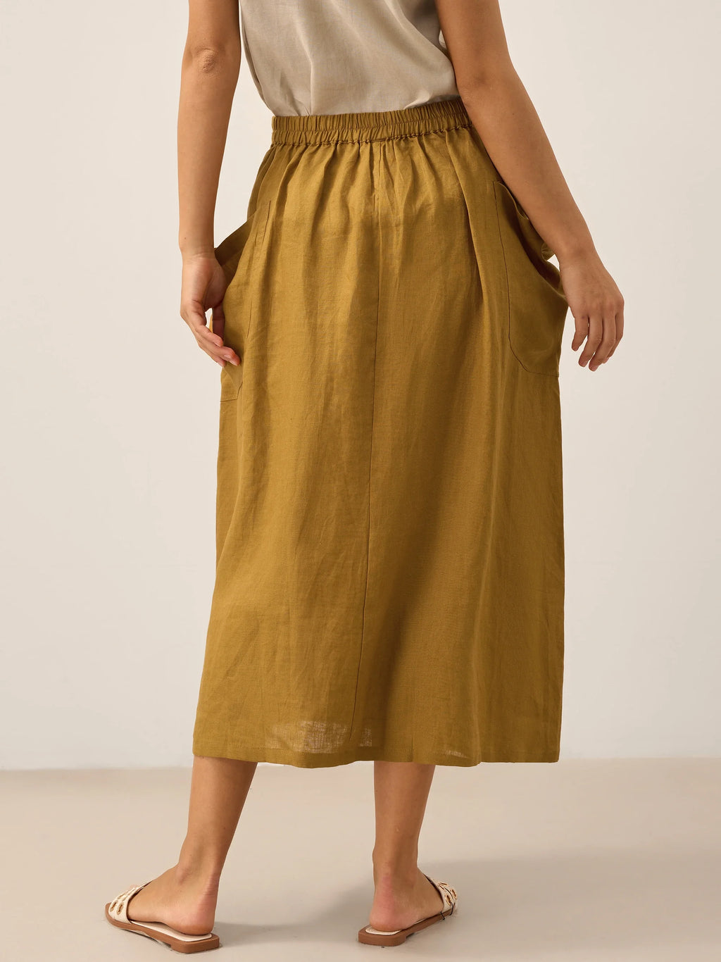 Person wearing a mustard yellow skirt on a plain background