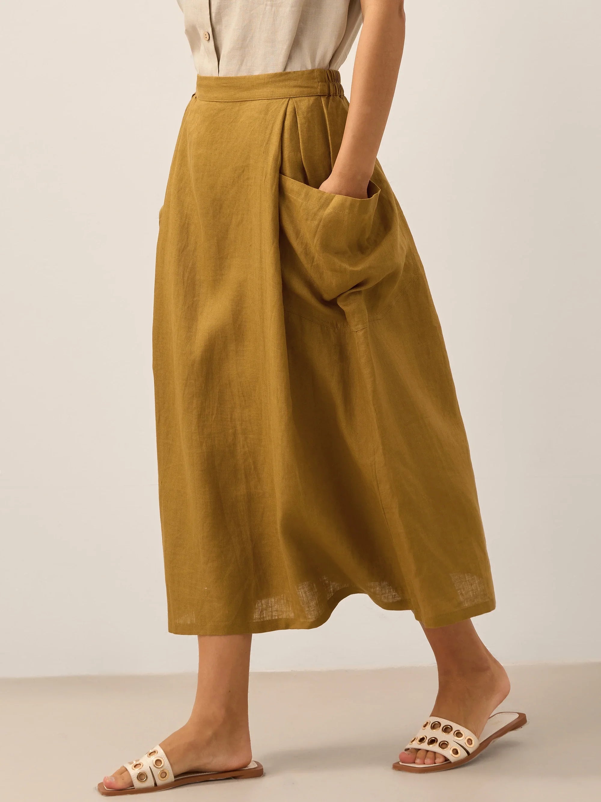 Person wearing a mustard yellow skirt with a plain background