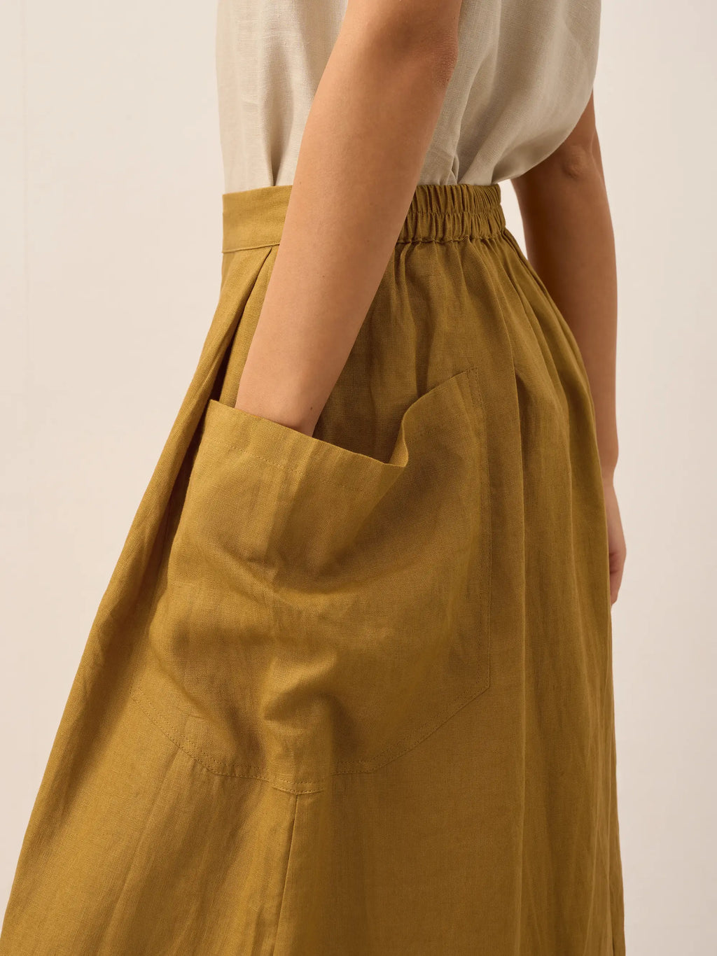 Person wearing a mustard yellow skirt with a plain background