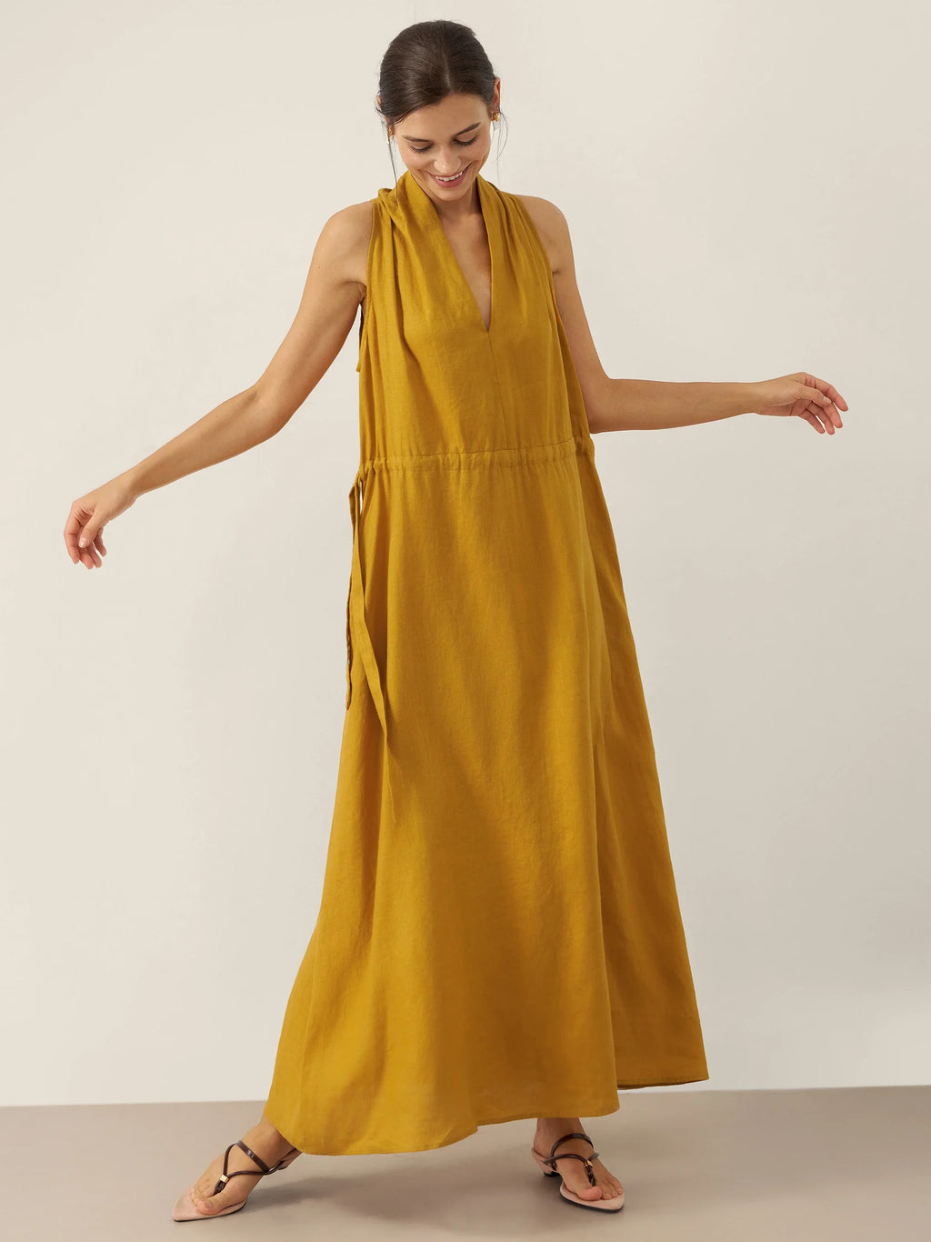 Woman wearing a mustard yellow dress on a plain background
