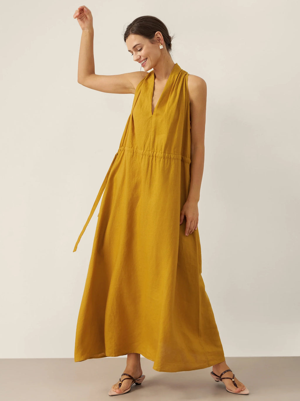 Woman wearing a mustard yellow dress against a plain background