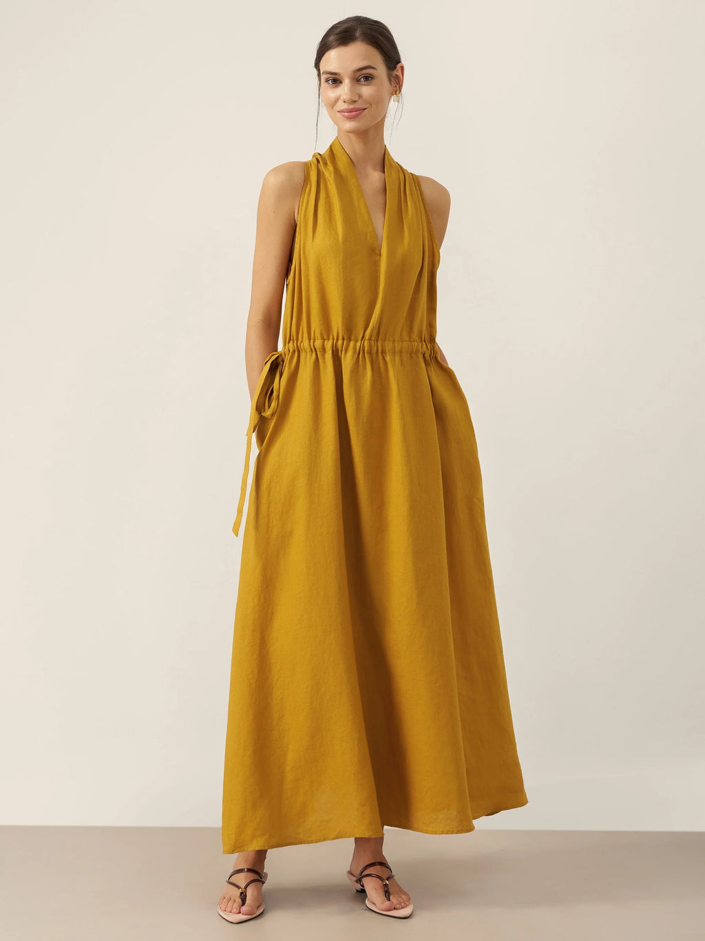 Woman wearing a mustard yellow dress against a plain background