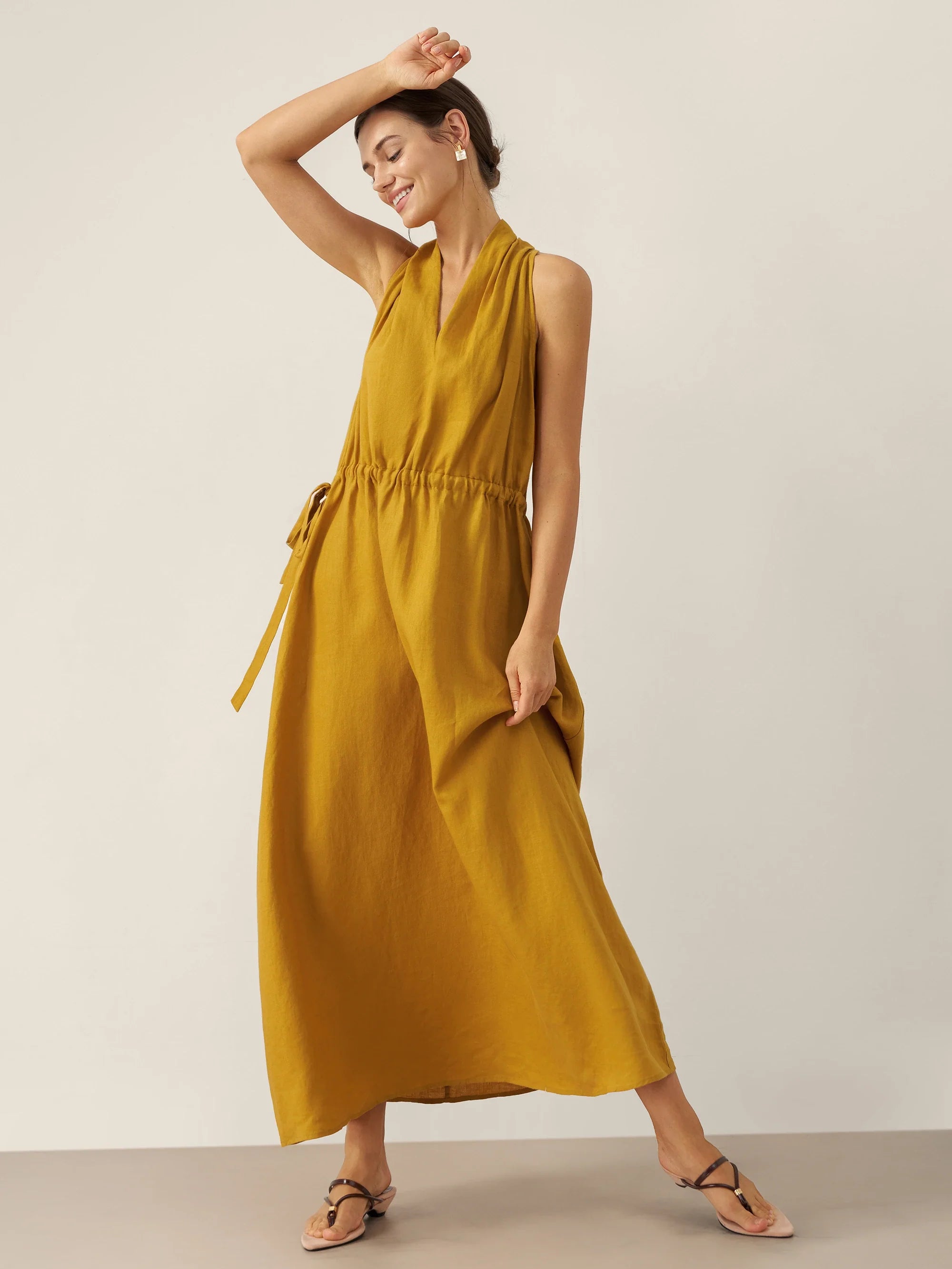 Woman wearing a mustard yellow dress against a plain background