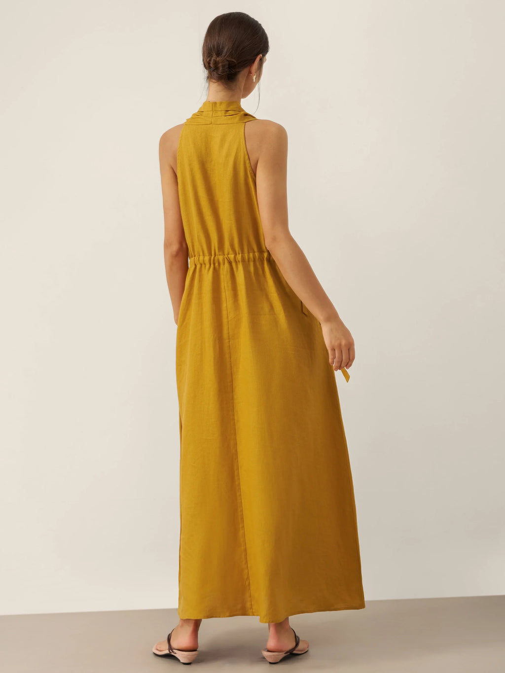Woman wearing a yellow dress against a plain background