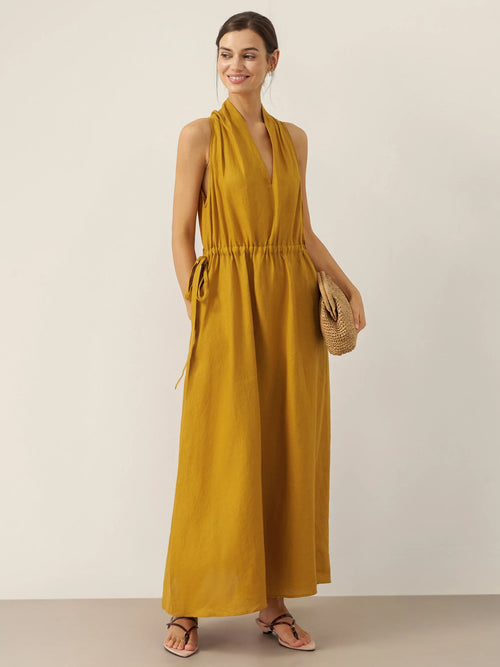 Woman wearing a mustard yellow dress against a plain background
