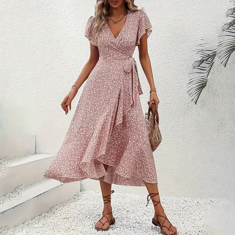 Woman wearing a pink floral dress against a white wall.