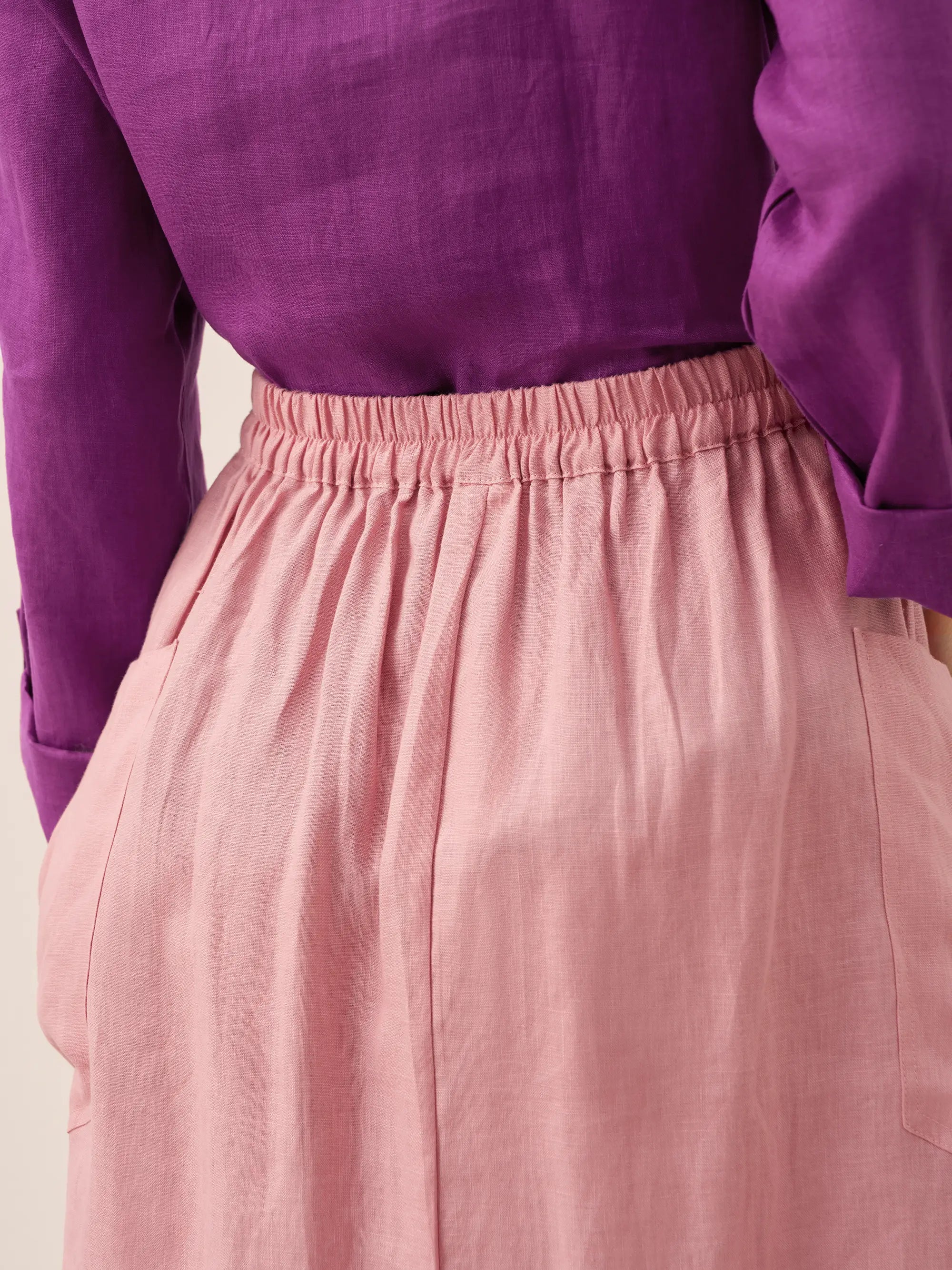 Purple long-sleeve top and pink skirt on a neutral background