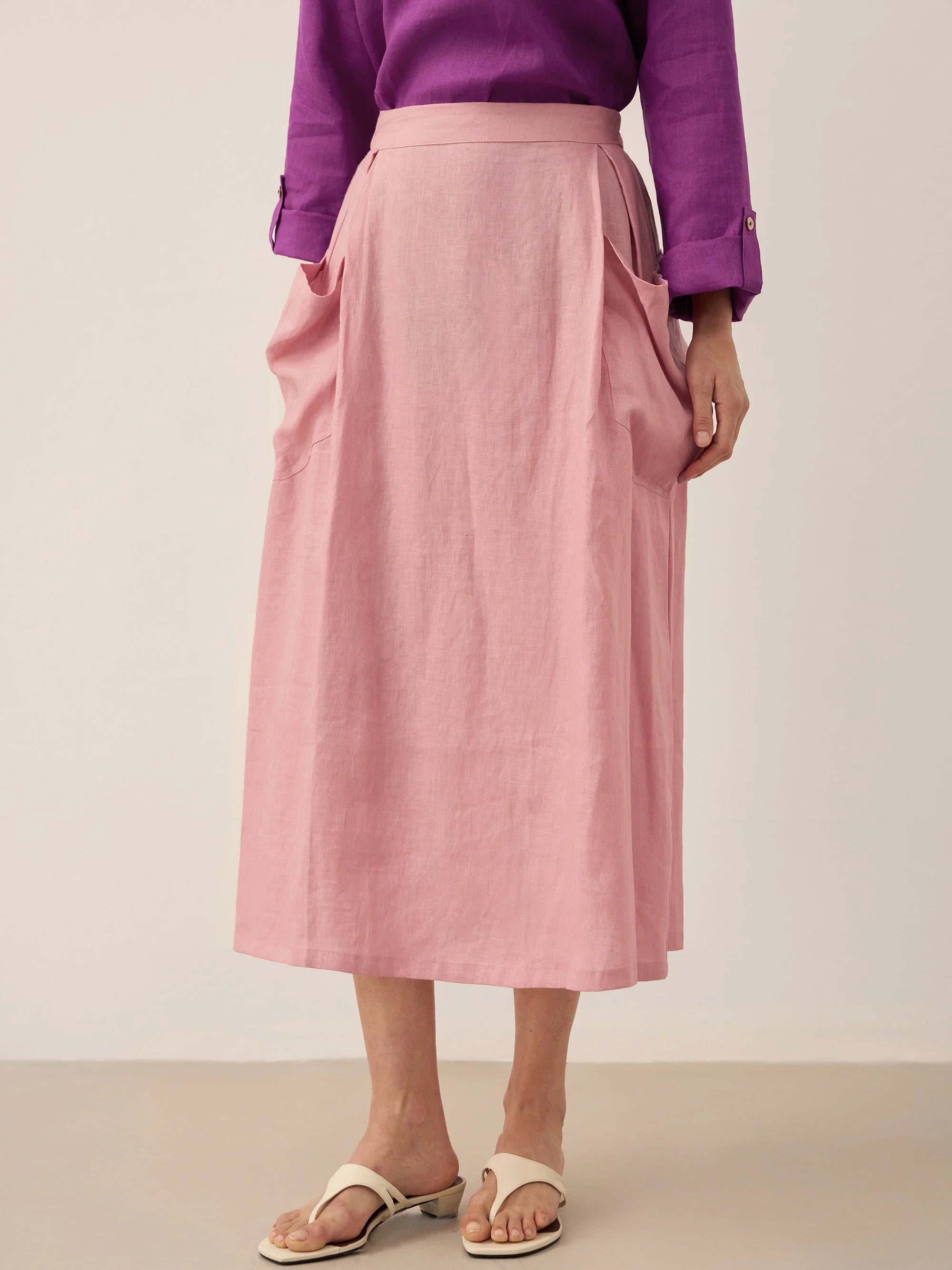 Person wearing a pink skirt and purple top on a plain background