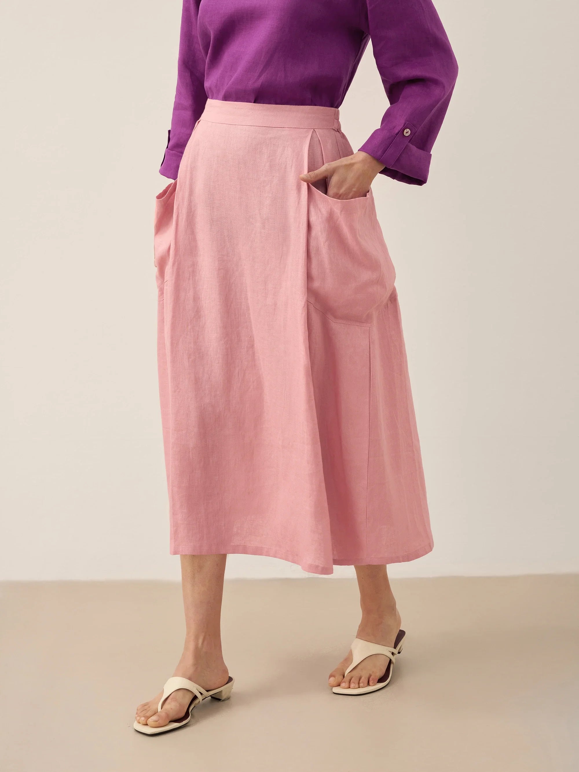 Person wearing a purple shirt and pink skirt on a plain background