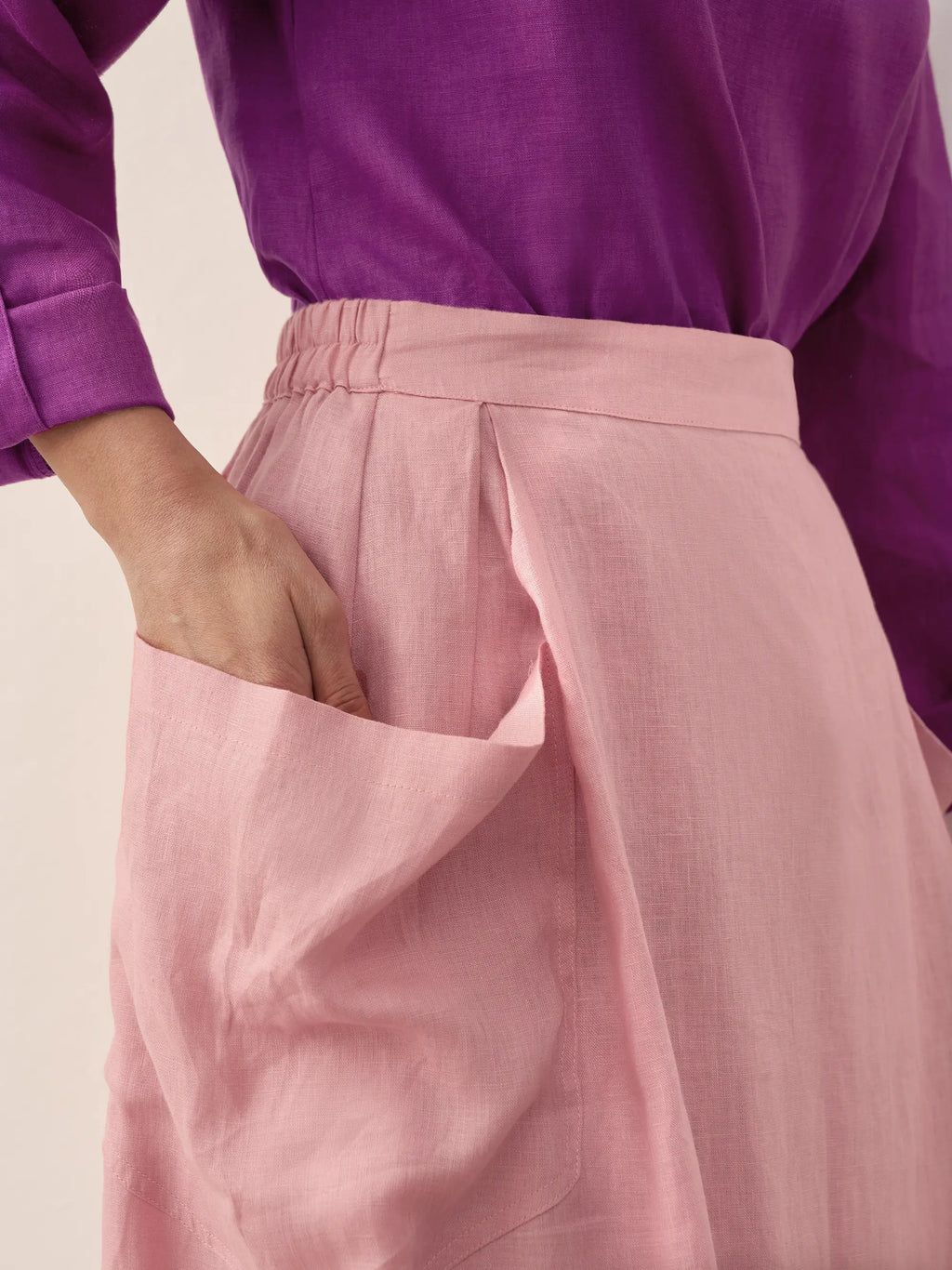 Person wearing a purple top and pink pants on a plain background