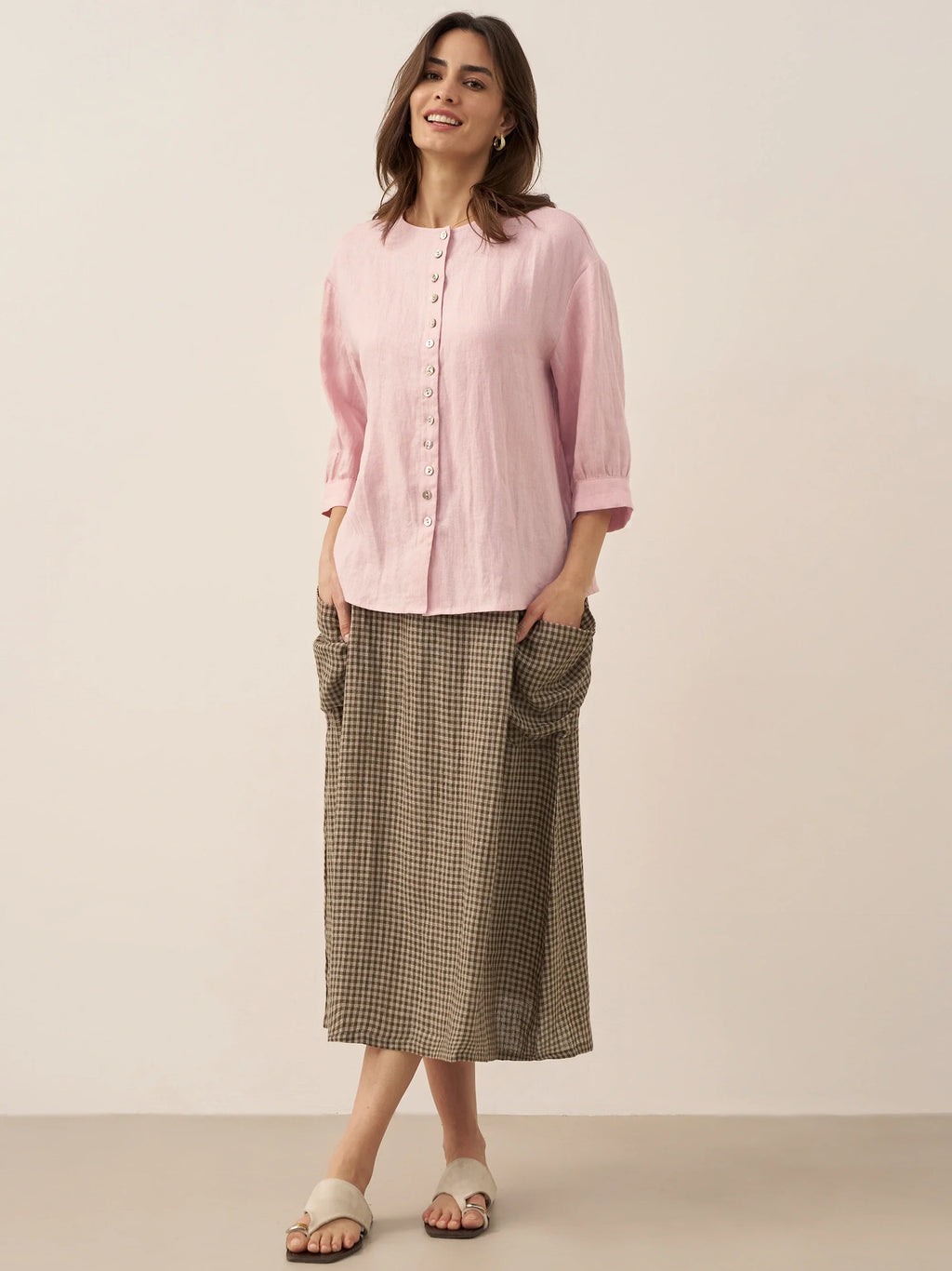 Woman wearing a pink shirt and plaid skirt on a plain background