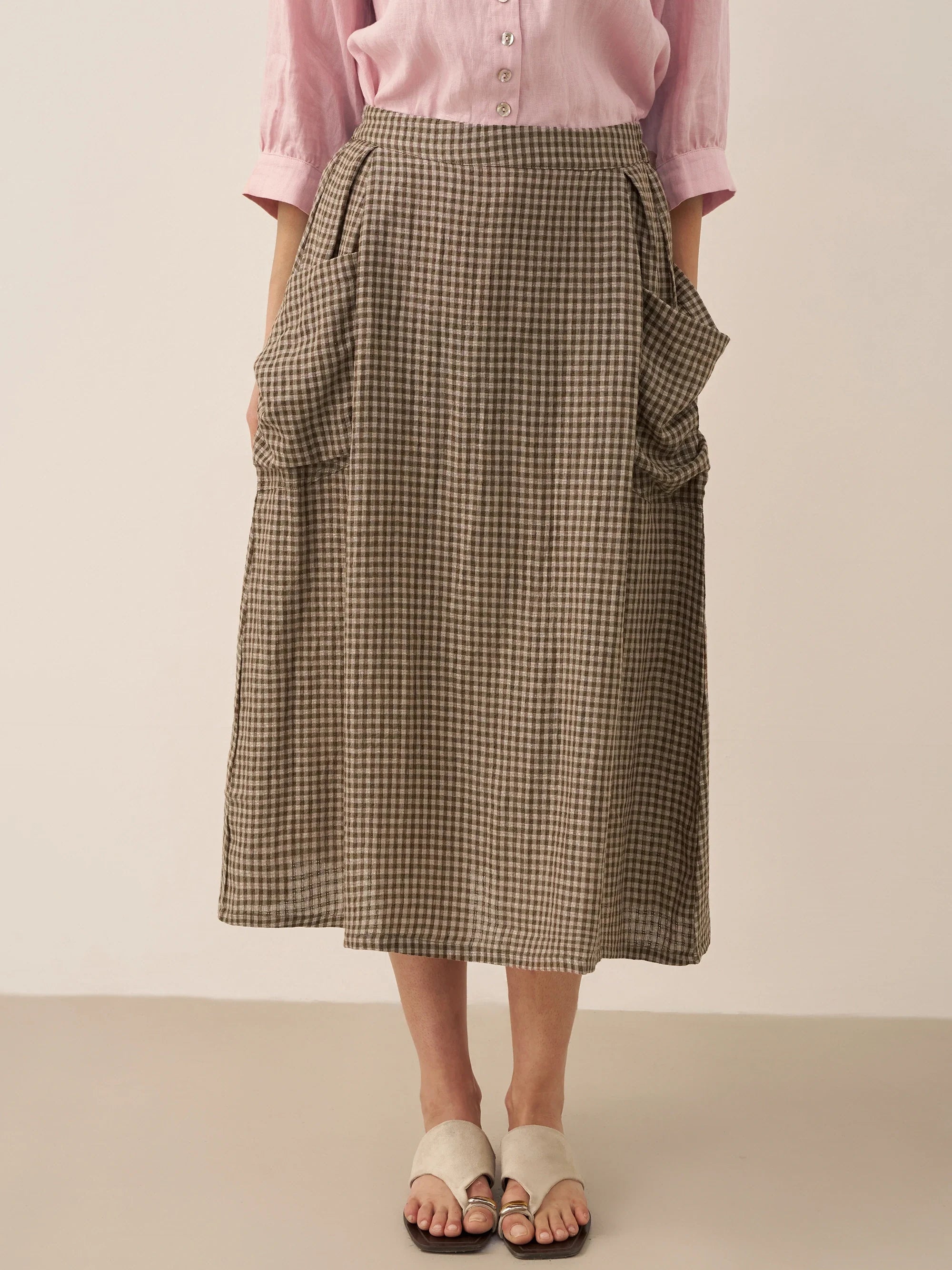 Person wearing a checkered skirt and pink shirt on a plain background
