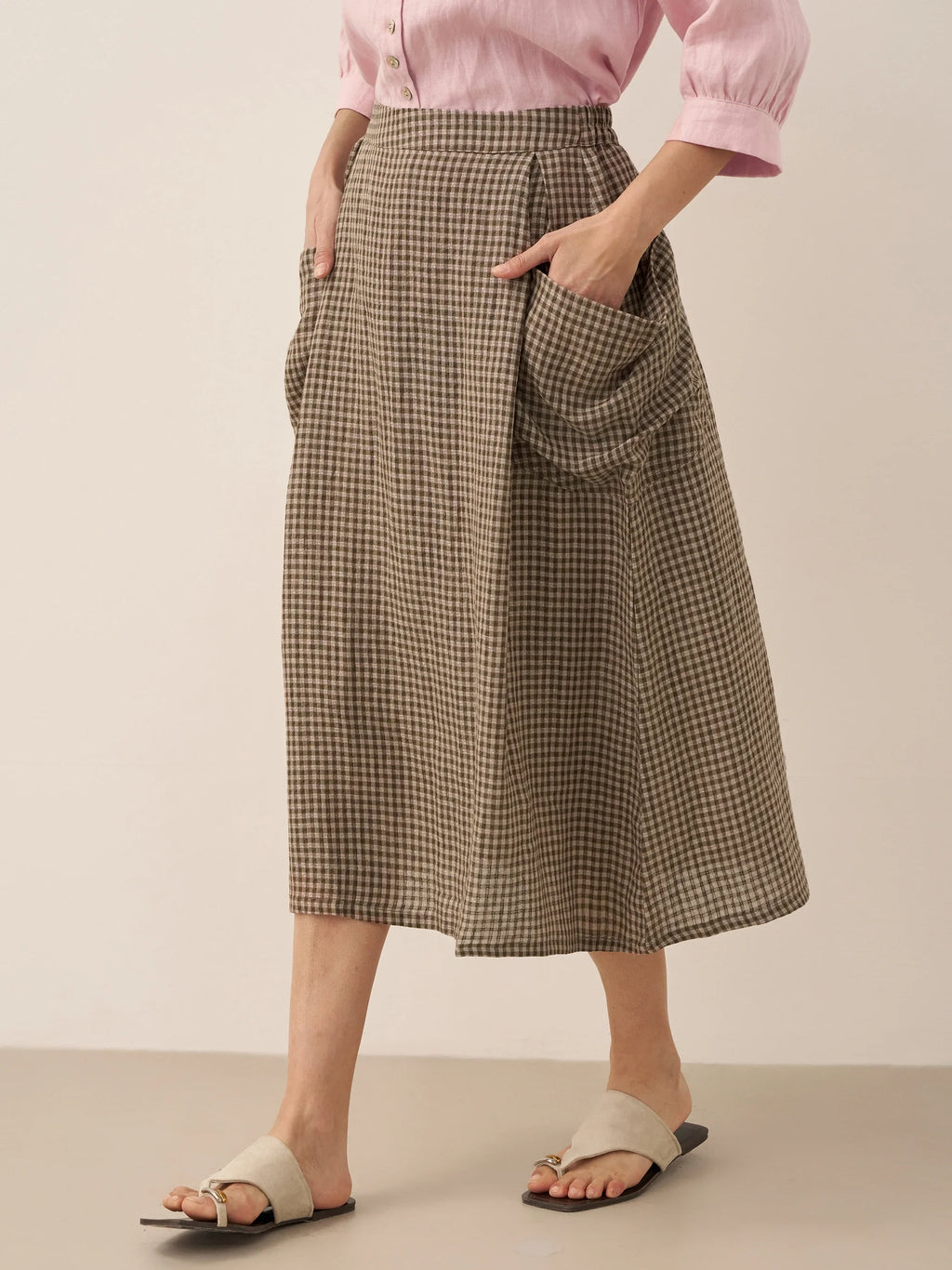 Person wearing a checkered skirt and pink shirt on a plain background
