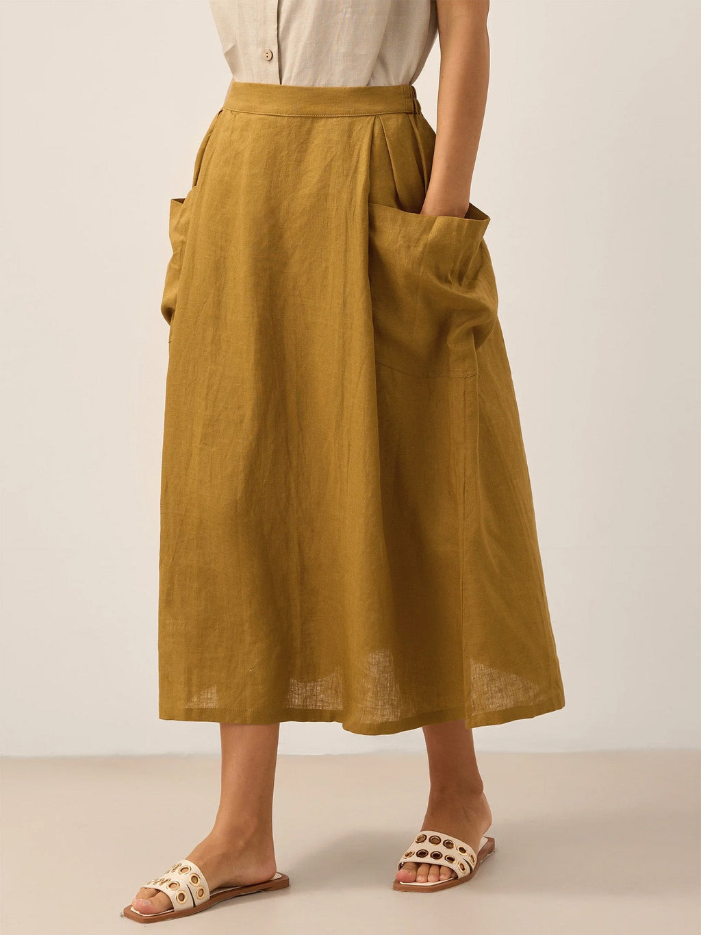 Person wearing a mustard yellow linen skirt with a plain background