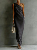 Woman wearing a one-shoulder dark gray dress against a plain background