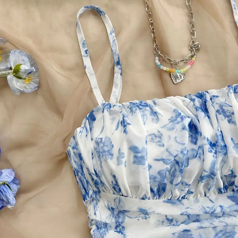Blue and white floral dress on a beige cloth with flowers and jewelry.