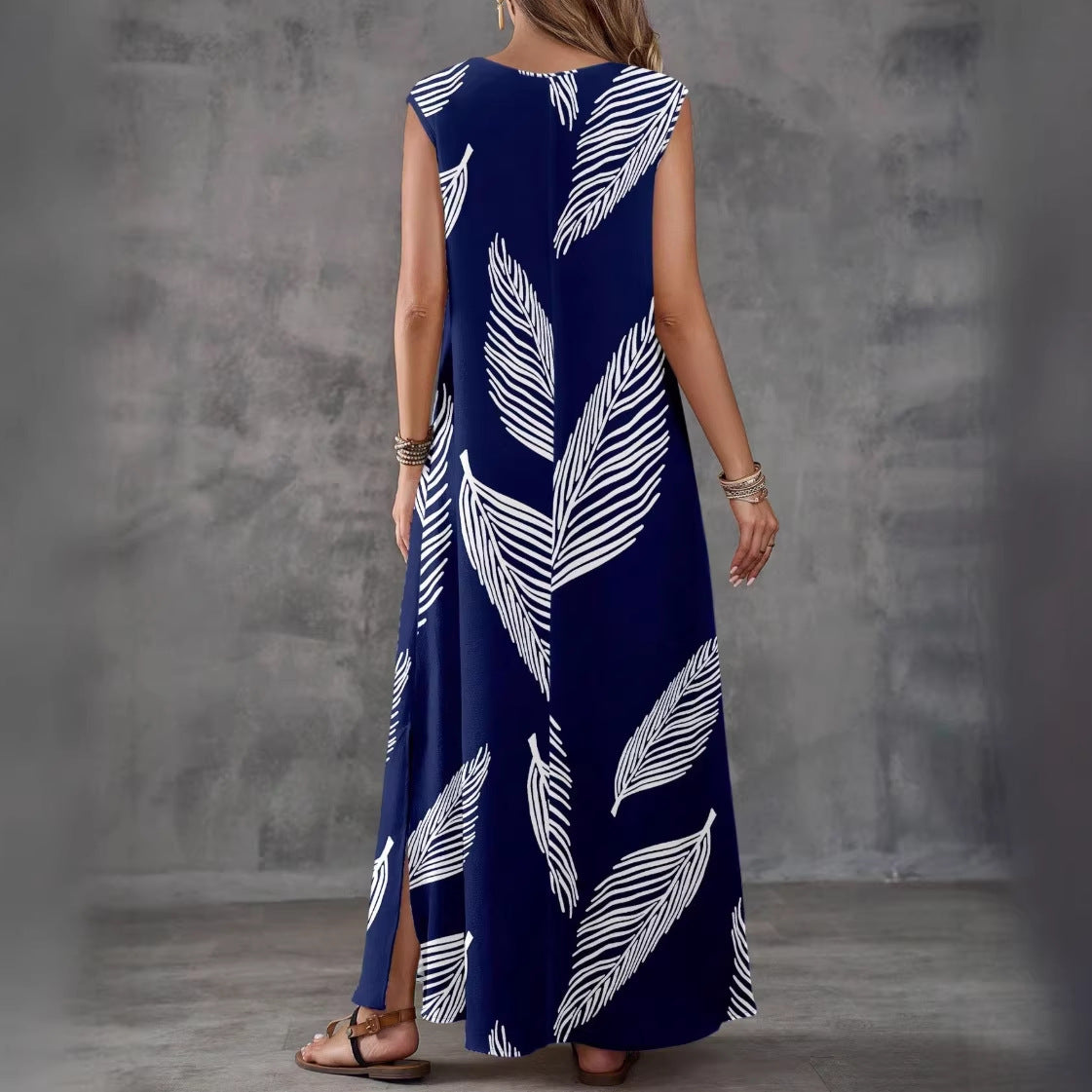Woman wearing a long navy dress with white leaf pattern against a gray background