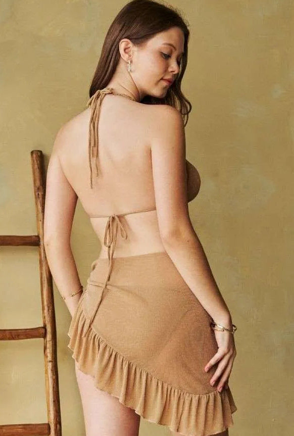 Woman wearing a taupe beige bikini with a ruffled skirt against a yellow background