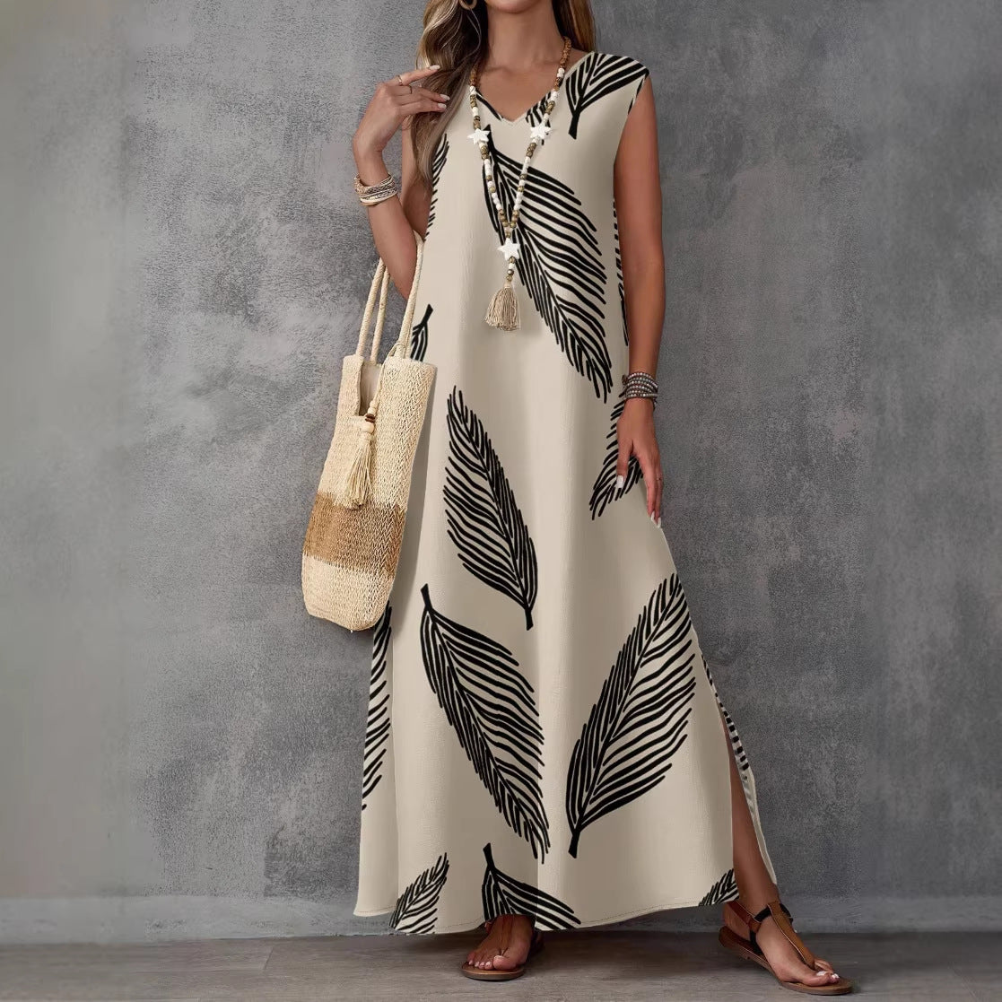 Woman wearing a long dress with black leaf pattern against a gray background