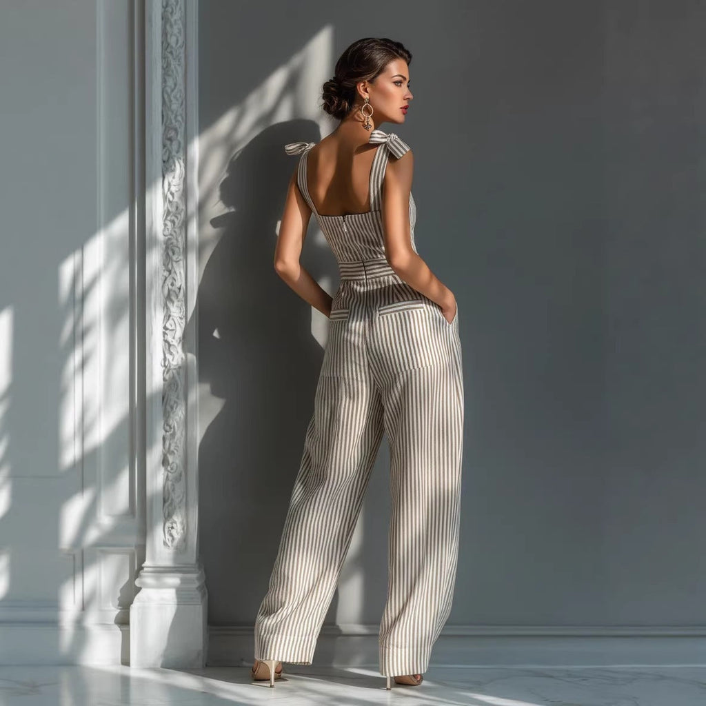 Woman in a striped jumpsuit standing against a light-colored wall with a decorative column.