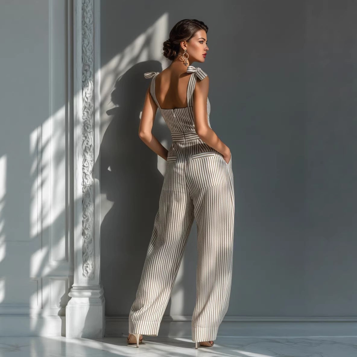 Woman in a striped jumpsuit standing against a light-colored wall with a decorative column.