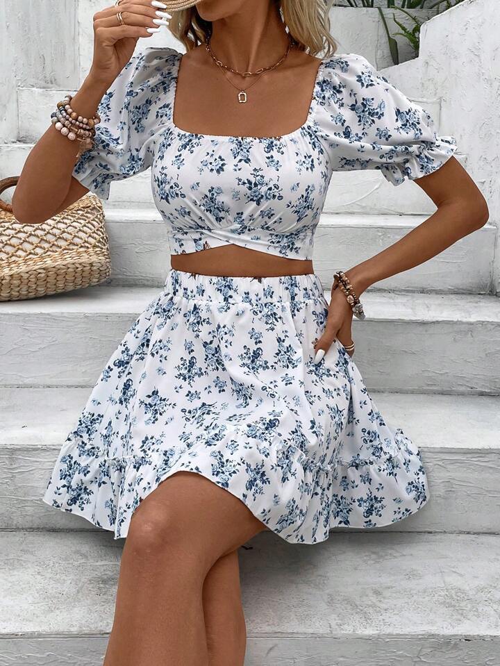 Woman wearing a blue and white floral dress sitting on a white staircase.