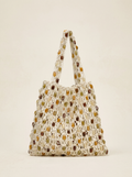 Woven handbag with multicolored stones on a beige background