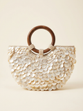 Handbag with wooden handle and shell-like embellishments on a beige background