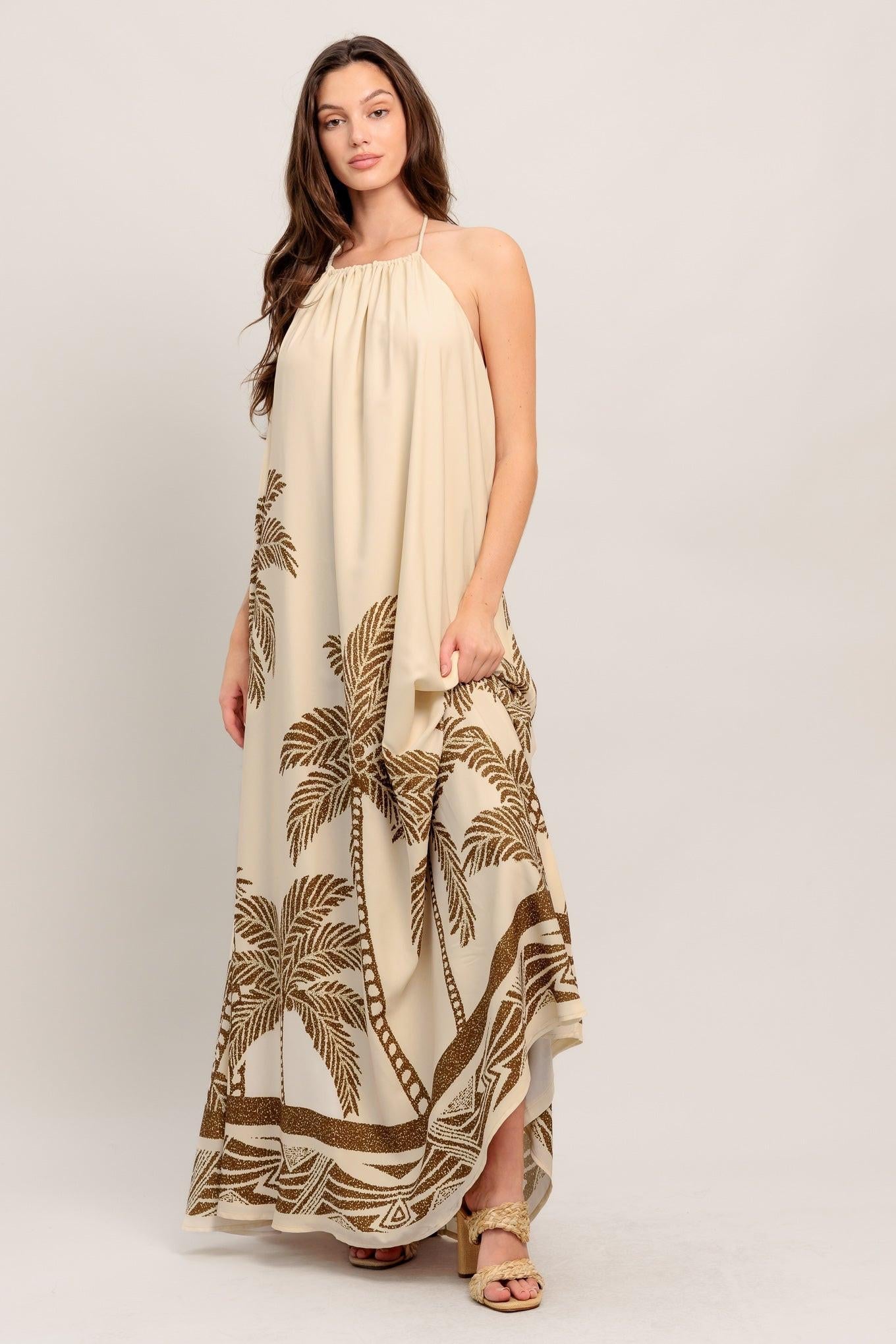 Woman wearing a beige halter neck dress with palm tree pattern on a white background