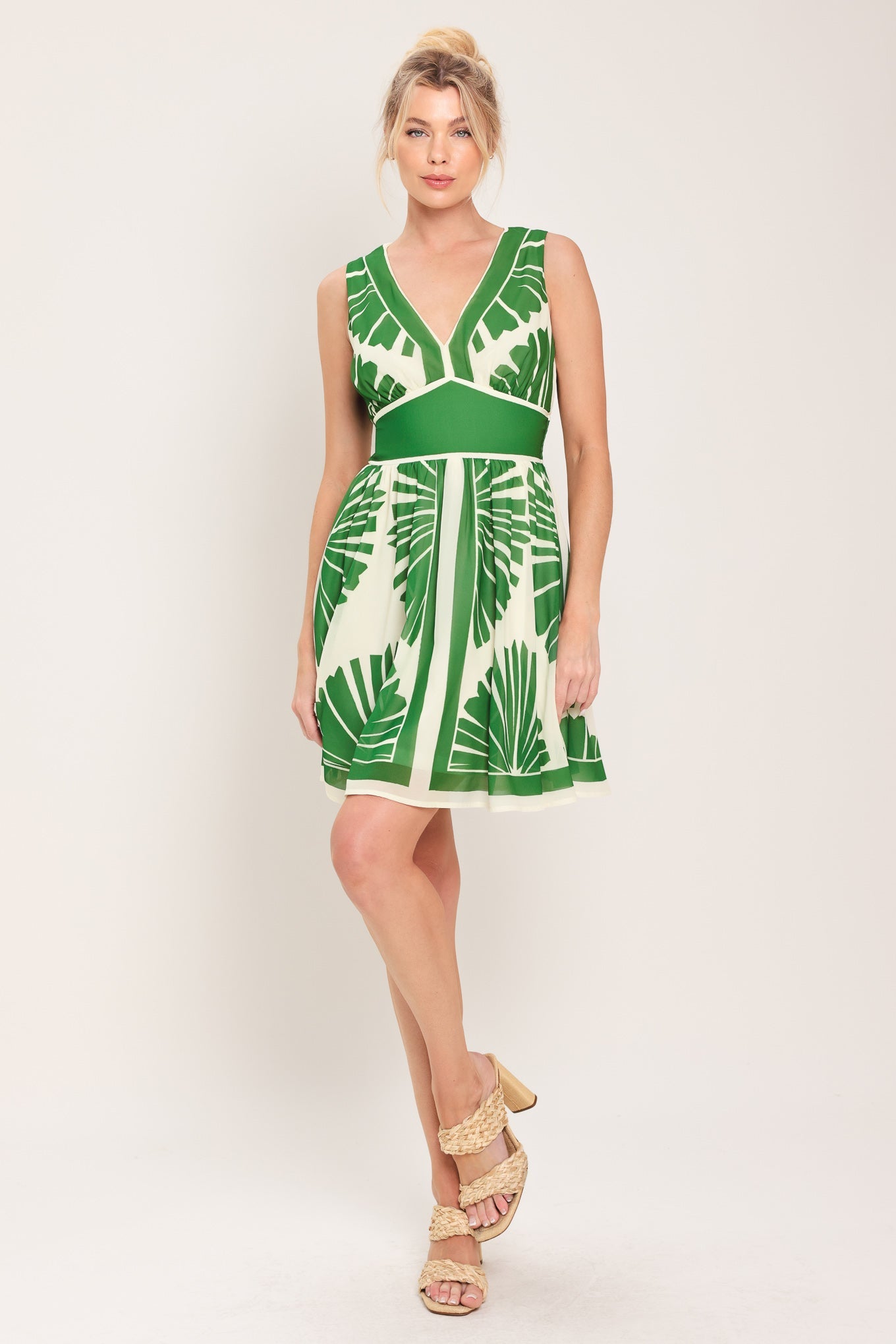Woman wearing a green and white dress with leaf pattern on a plain background