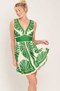 Woman wearing a green and white leaf-patterned dress against a plain background