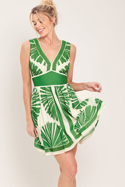 Woman wearing a green and white leaf-patterned dress against a plain background