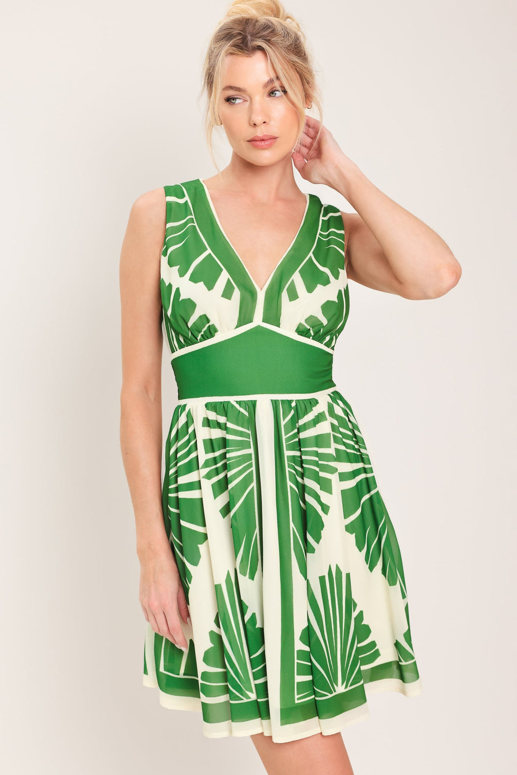 Woman wearing a green and white patterned dress against a plain background